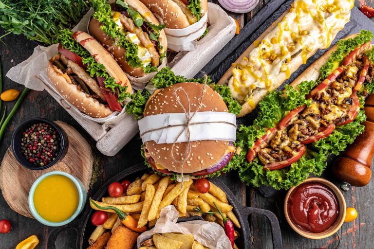 Hot dogs, hamburgers and french fries on wooden table. fast food snacks